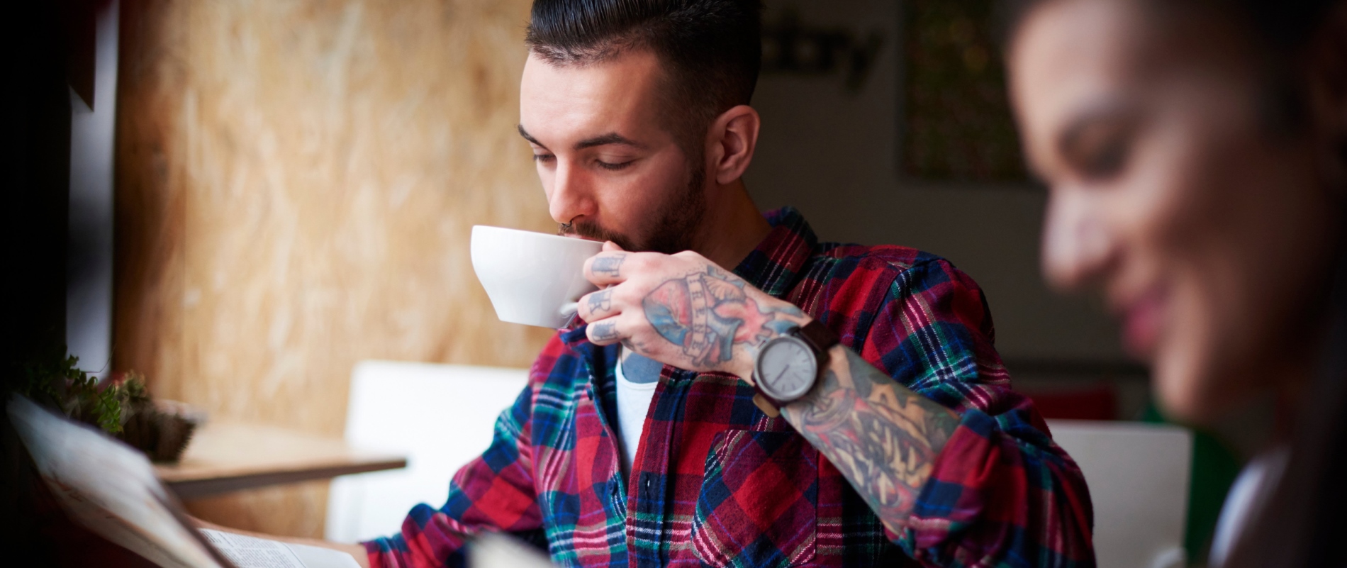 Pärchen sitzt in einem Café, er liest Zeitung